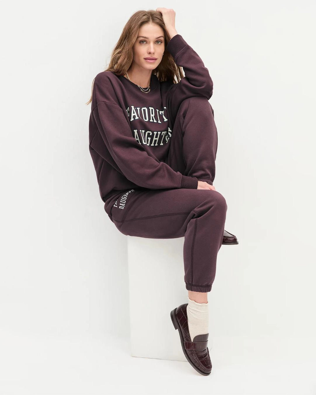 Woman wearing a maroon 'FAVORITE DAUGHTER' sweatshirt and matching sweatpants
