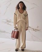 A woman wearing wide leg knit pant in beige with a black stripe on the sides