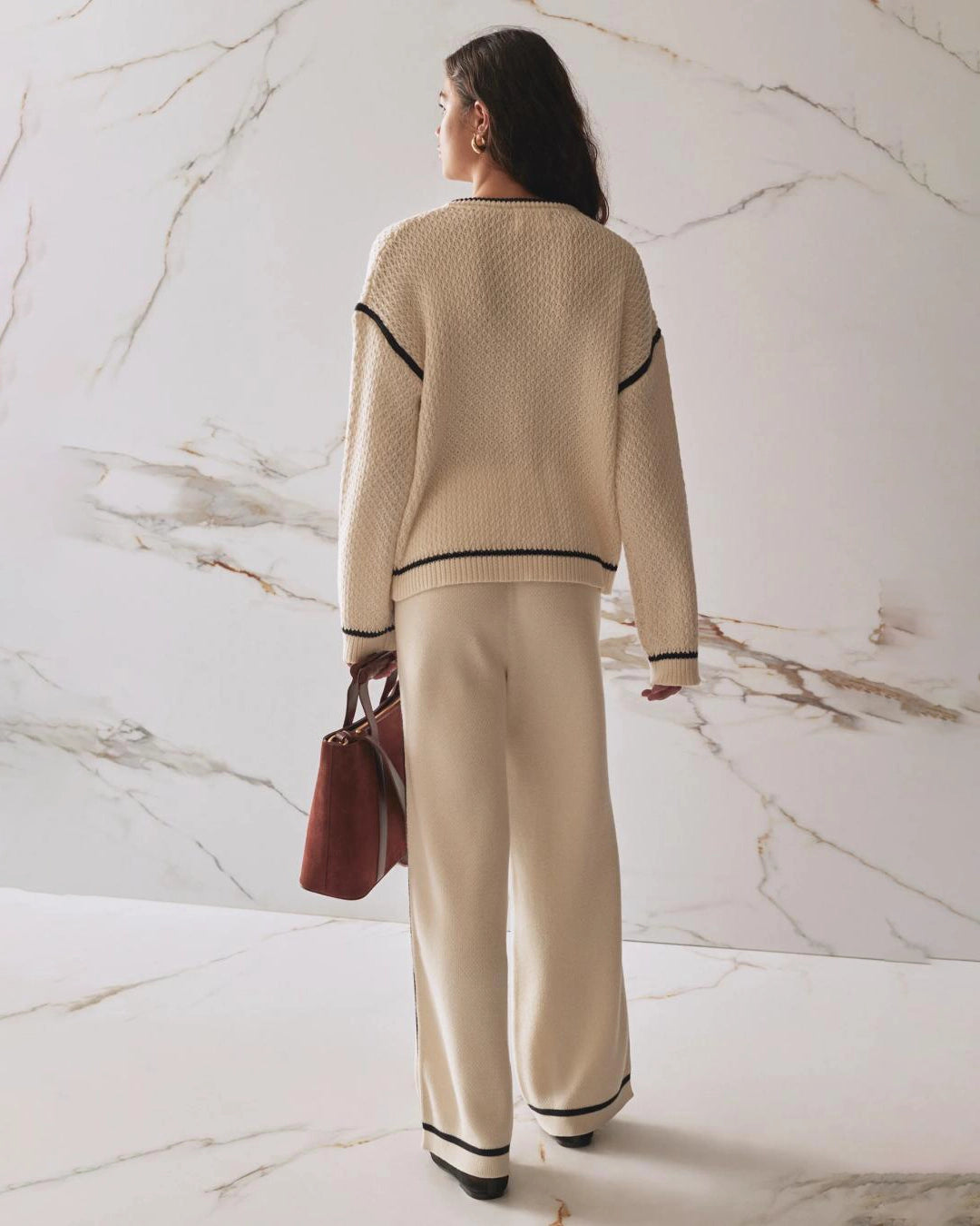 A woman wearing wide leg knit pant in beige with a black stripe on the sides