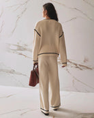 A woman wearing wide leg knit pant in beige with a black stripe on the sides