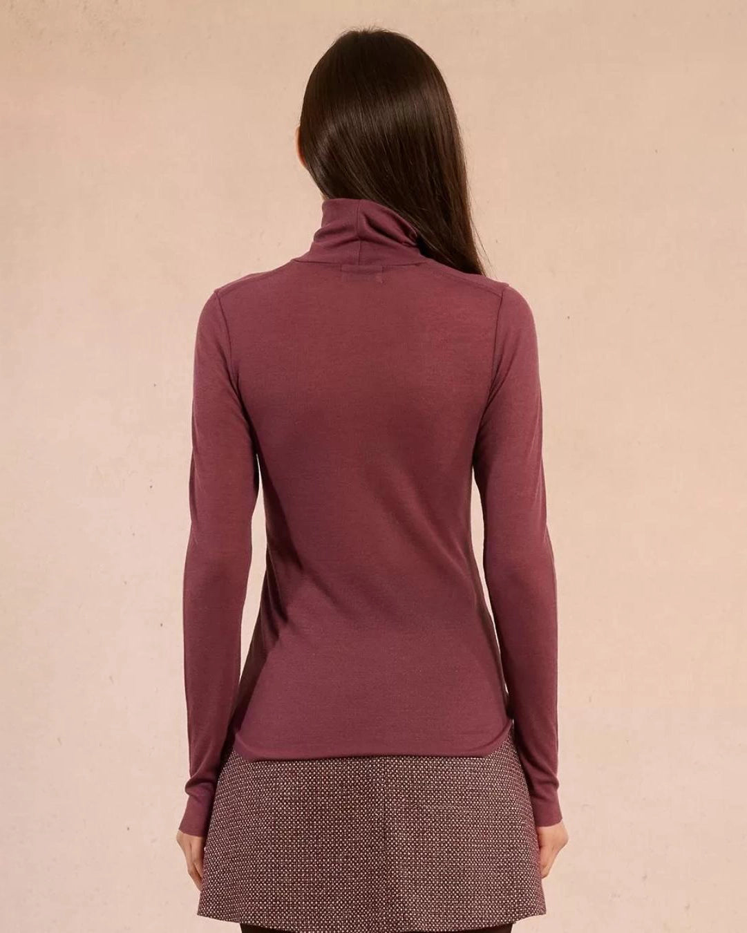 Woman wearing a rust coloured turtleneck sweater