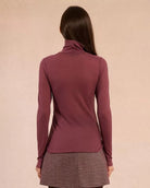 Woman wearing a rust coloured turtleneck sweater