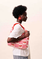 pink and white checkered hand bag with red fish on it