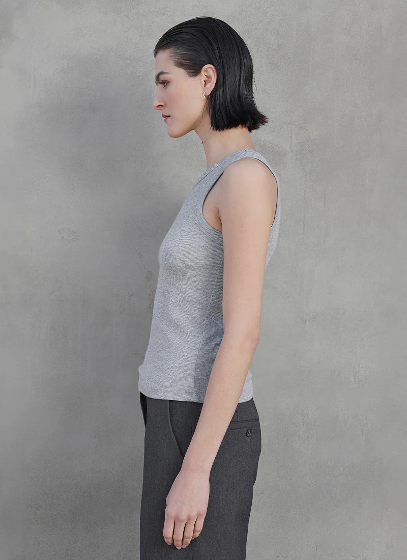A woman wearing a grey ribbed tank top and grey trousers