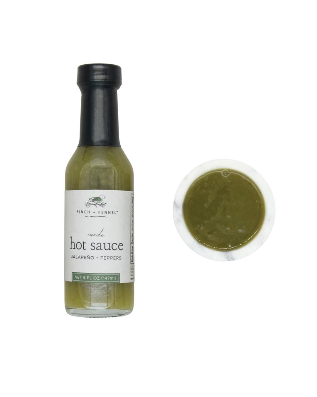 Bottle of hot sauce with a label and a small container of sauce on a white background