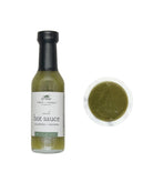 Bottle of hot sauce with a label and a small container of sauce on a white background
