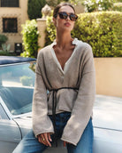 Woman wearing a beige knit cardigan with a thin belt