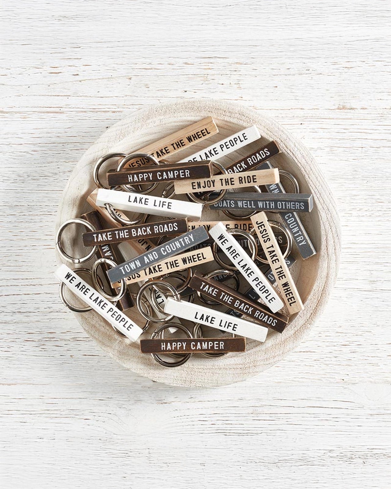 a bowl of wooden keychains with fun sayings on them