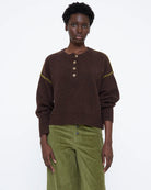 brown knit sweater with buttons half down and a green detail on sleeve