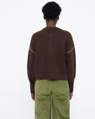 brown knit sweater with buttons half down and a green detail on sleeve
